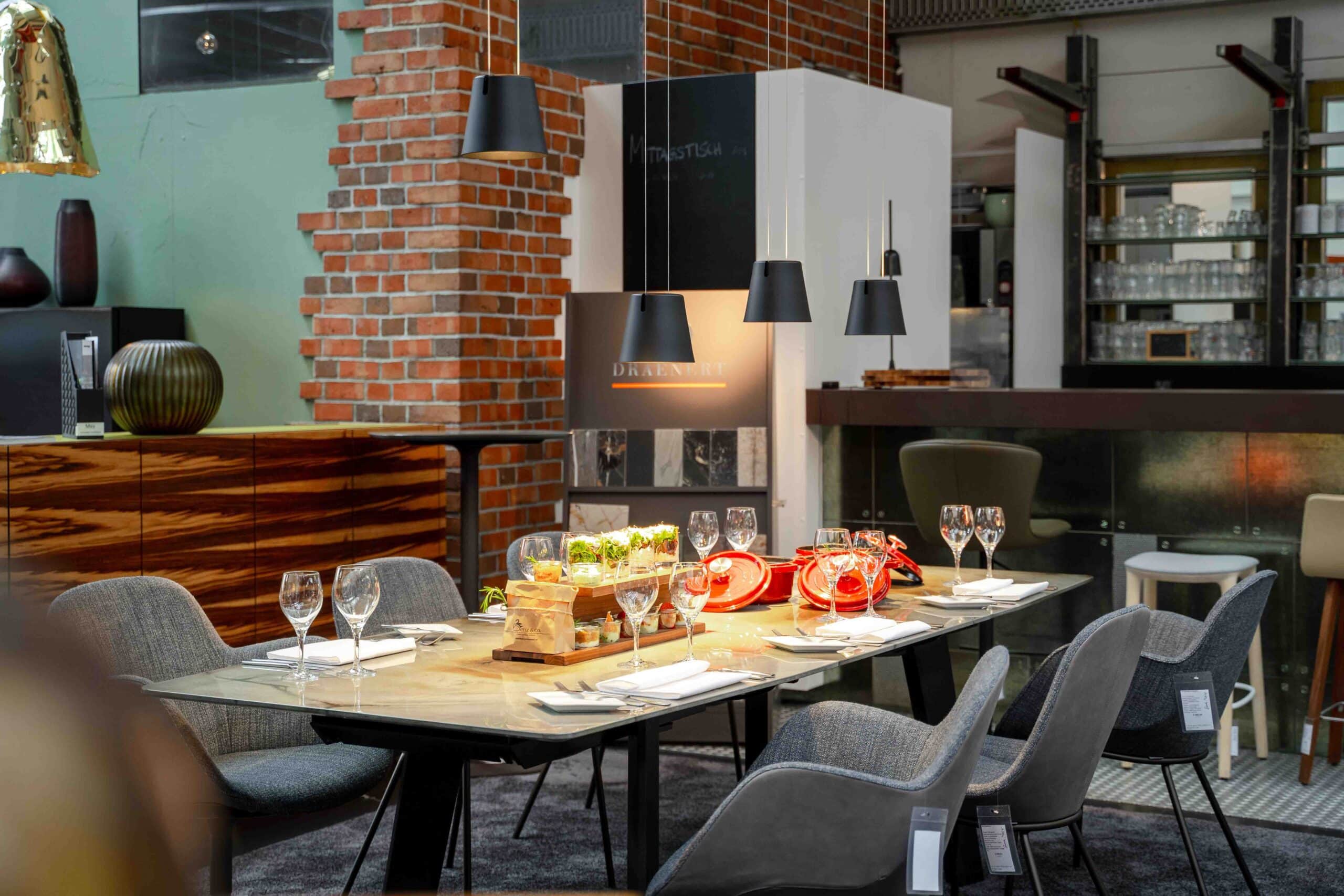 Eingedeckter Tisch mit Tischbuffet aus roten Töpfen und Holzetagere mit in Gläsern angerichteten Salaten.