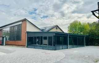 Aussenansicht des Anbaus BlackBox mit großen Fensterfronten und schwarzen Verkleidungen.