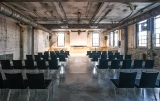 Industriehalle bestuhlt mit Leinwand.