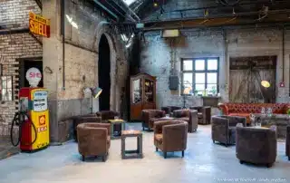 Lounge mit braunen Ledersesseln in rustikalem Ambiente einer Industriehalle.