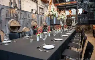 Feierlich gedeckter Tisch in rustikal industriellem Ambiente einer ehemaligen Industriehalle.