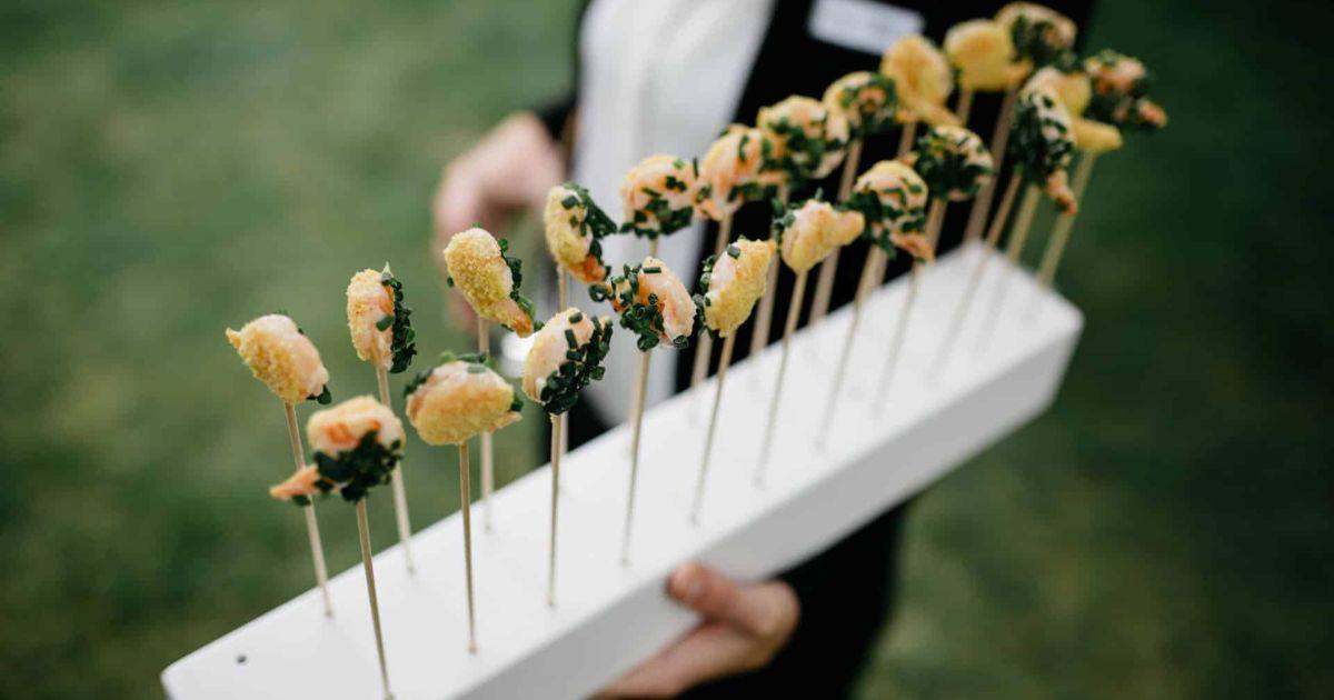 Catering Private Feiern 17 Ein Kellner serviert stilvoll arrangierte Snacks auf einem Tablett bei einem Event.