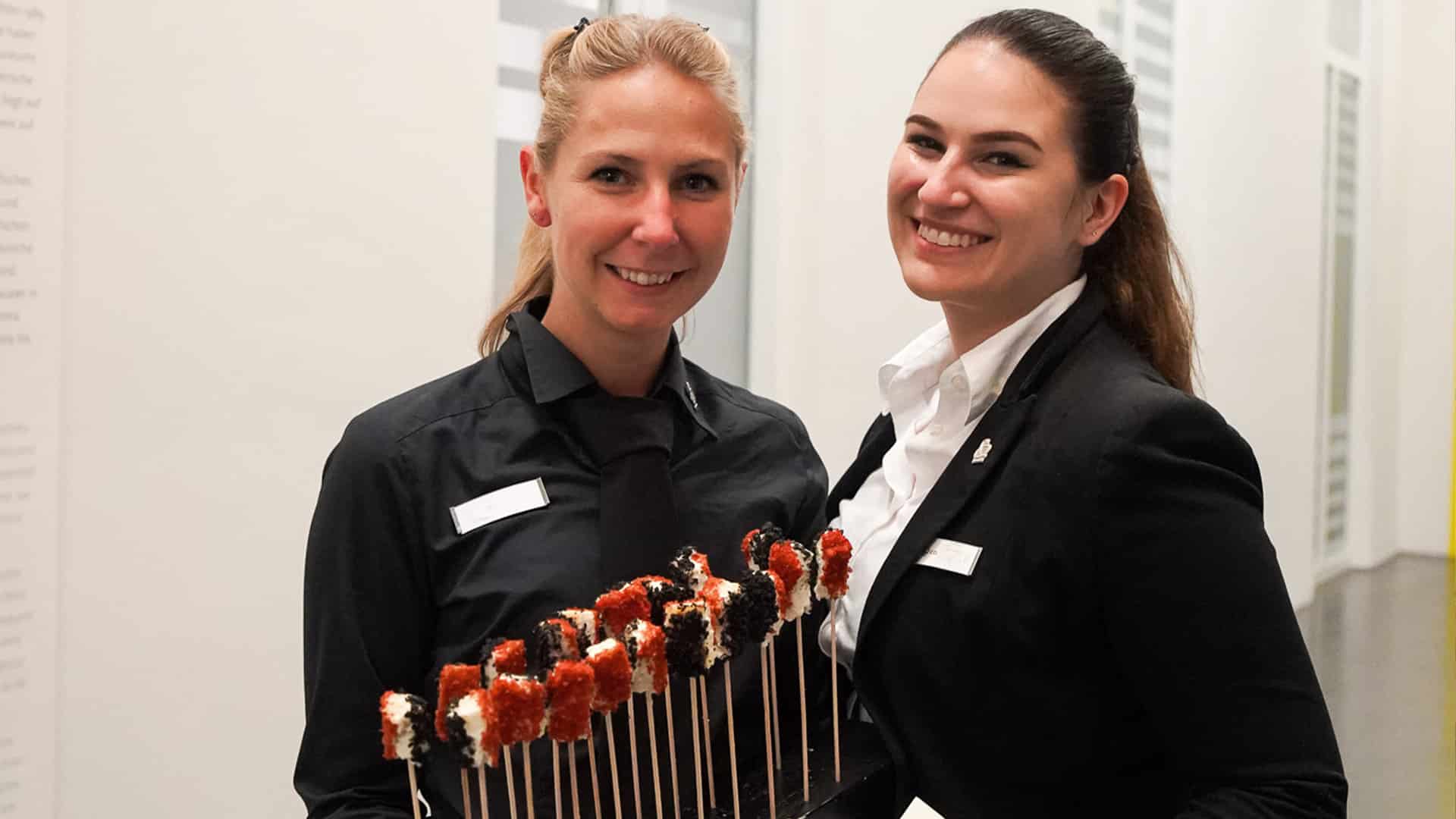 Strahlende Servicekräfte mit Fingerfood.